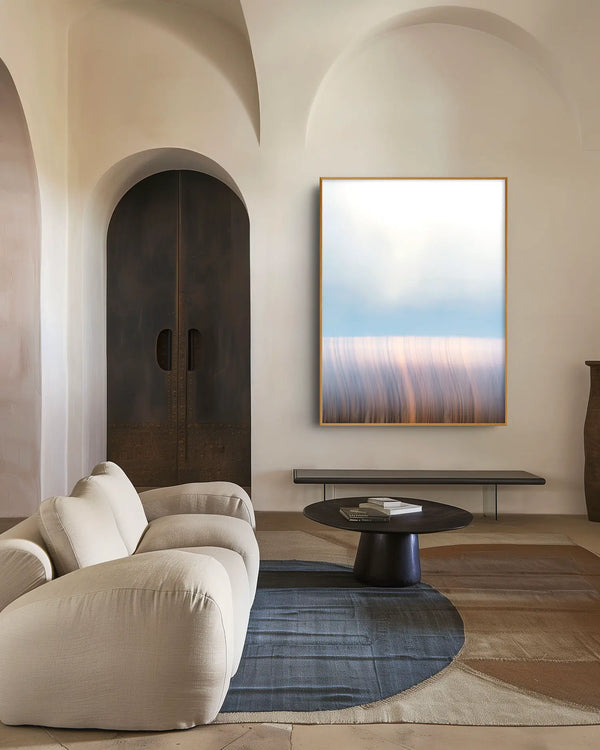Echoes of Light 14 als gerahmtes Wandbild vor weißer Wand im Wohnzimmer – zarte Blau-, Rosé- und Cremetöne mit feinen vertikalen Strukturen.